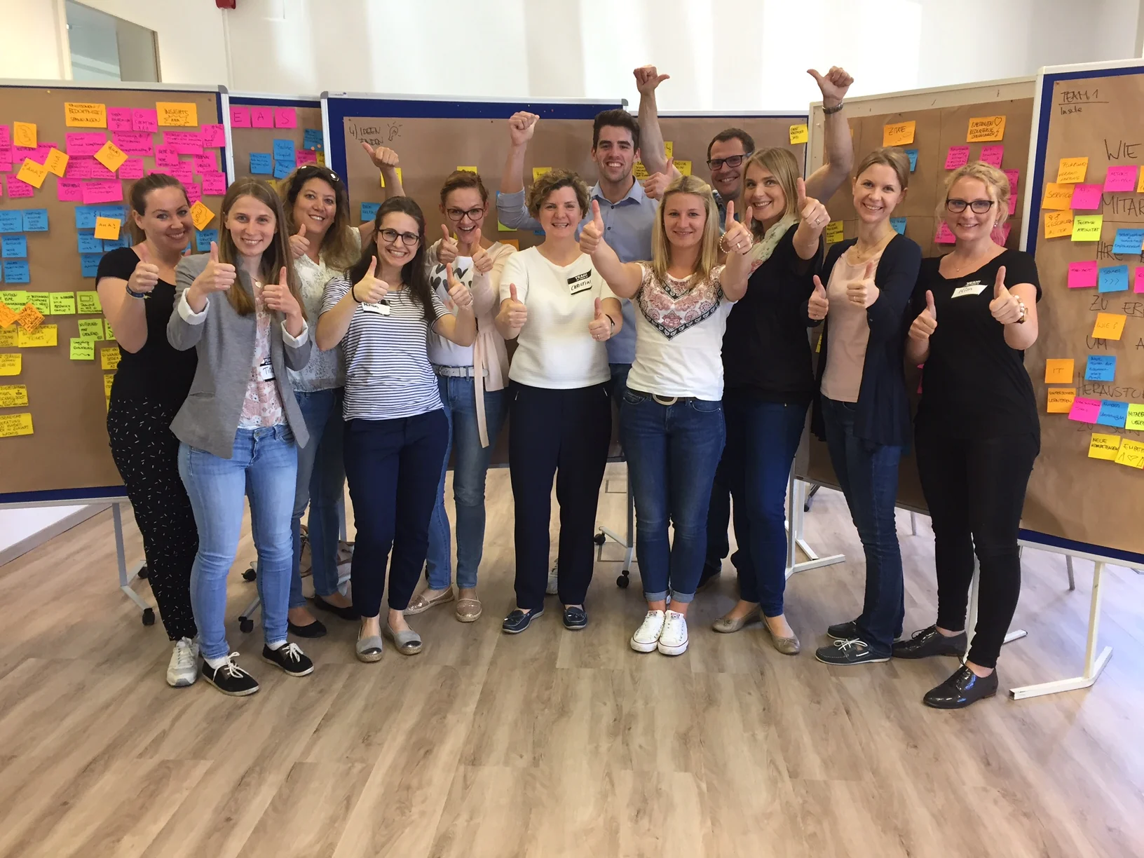 Eine Workshopgruppe steht vor Stellwänden mit farbigen Notizzetteln.